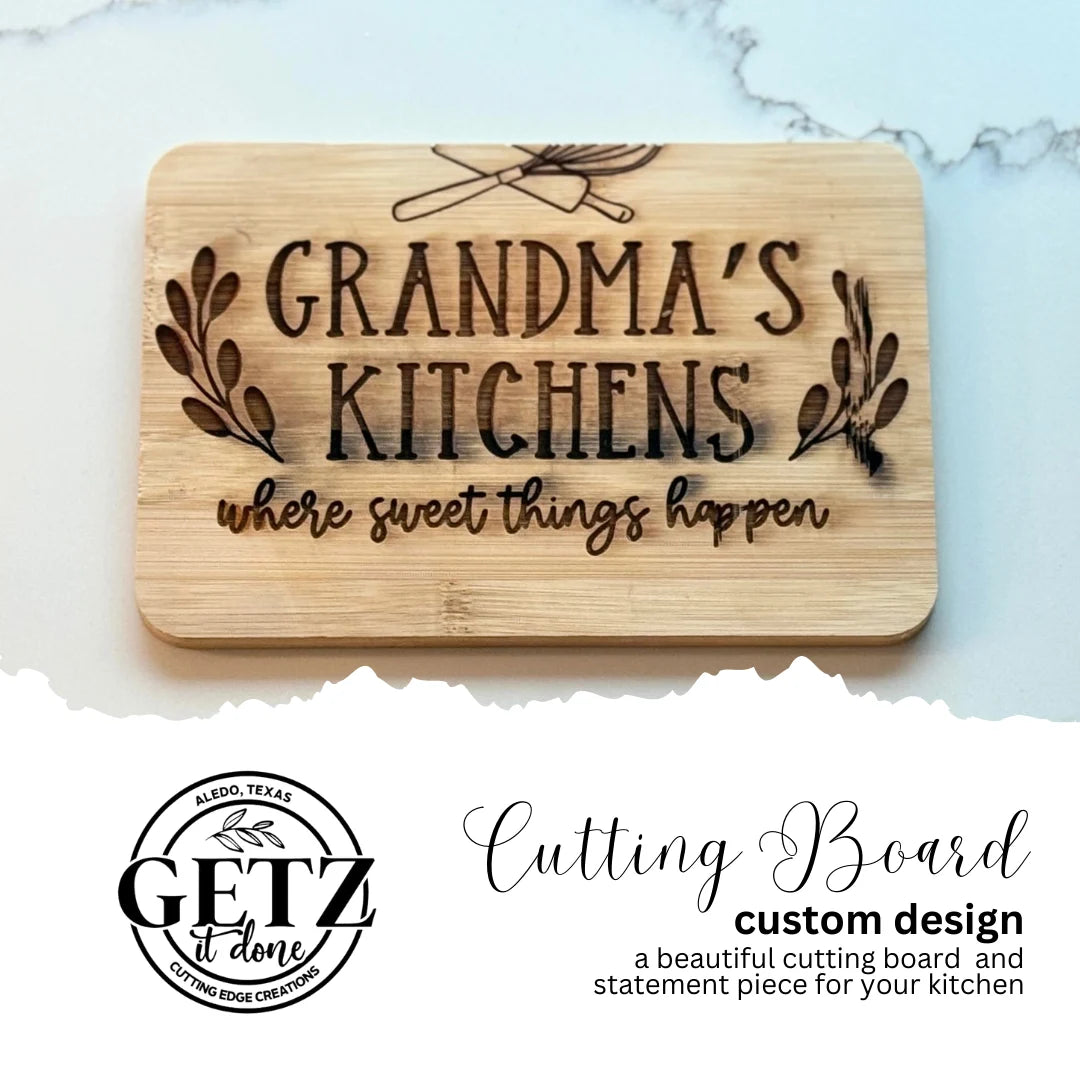 Wooden cutting board engraved with GRANDMAS KITCHEN where sweet things happen featuring utensils and foliage design. Below, a logo reads GETZ it done with Aledo, Texas. Text describes it as a custom cutting board and a kitchen statement piece.