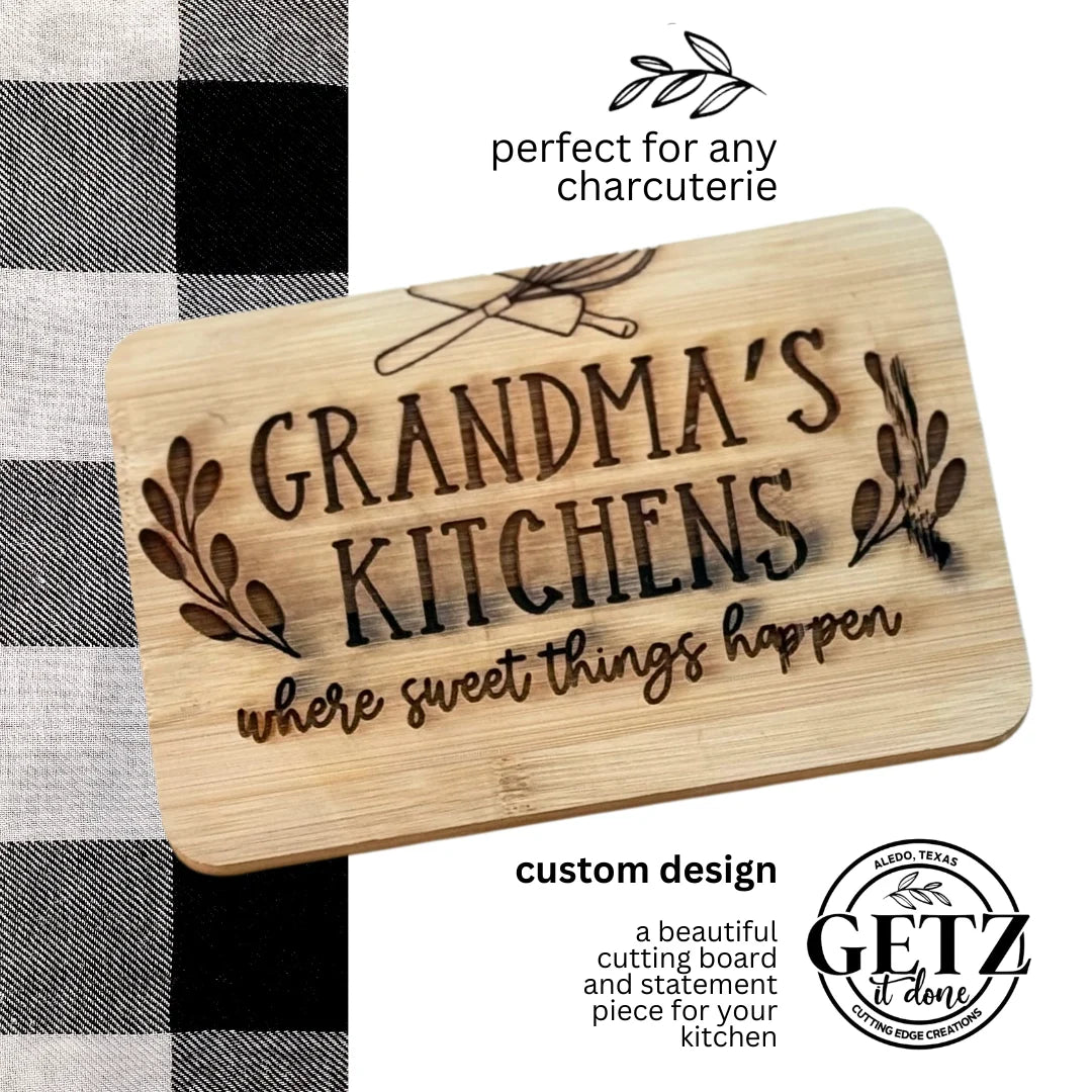 Cutting board with engraved text GRANDMAS KITCHENS where sweet things happen and black floral designs. Top text says perfect for any charcuterie, with utensil icons. Bottom text promotes custom design, featuring Getz logo. Black and white checkered cloth partially visible.