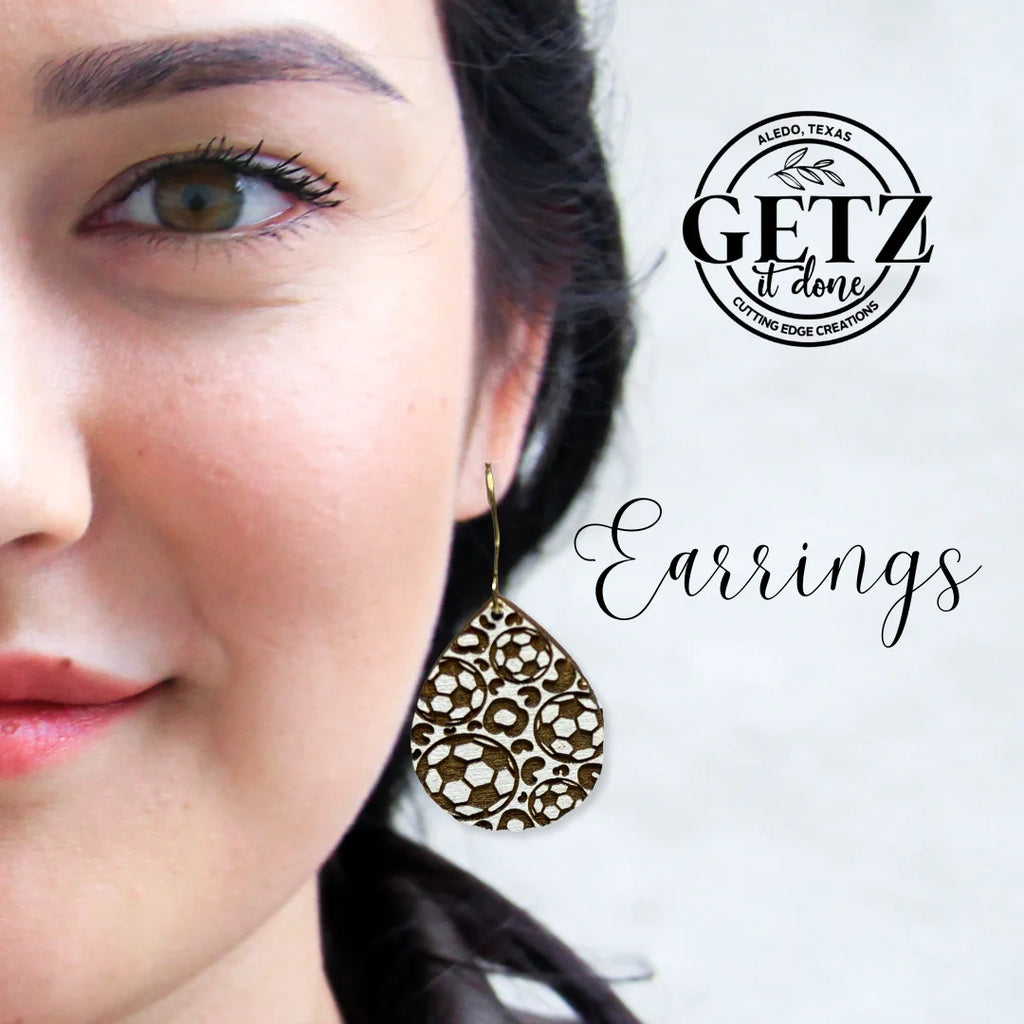 Close-up of a person wearing a teardrop-shaped, intricately patterned earring. The background has a logo that reads GETZ it done, Aledo, Texas, Cutting Edge Creations. The word Earrings is written in elegant script next to the persons face.