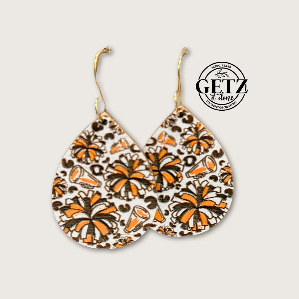 Teardrop-shaped earrings with a tropical cocktail print featuring orange, brown, and black colors on a white background. The background has a faint beige hue. The design includes palm trees, drinks, and swirls. The top right corner has the Getz It Done logo in black.