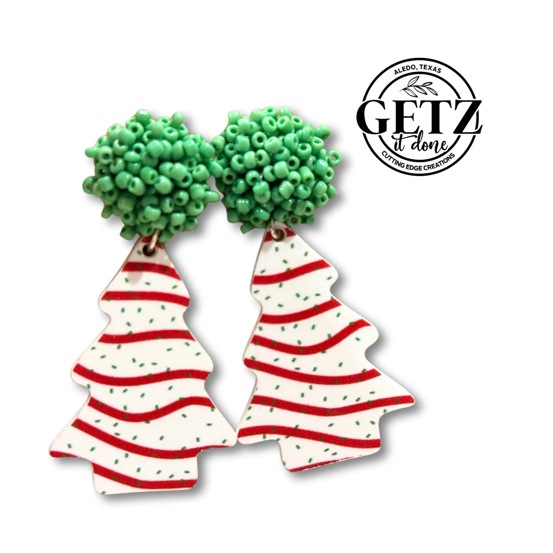 Festive earrings featuring Christmas tree designs. The tops are green bead clusters, resembling tree tops. Below are white tree shapes with red wavy stripes and green dots. The brand logo GETZ it done is visible in black text on the upper right.