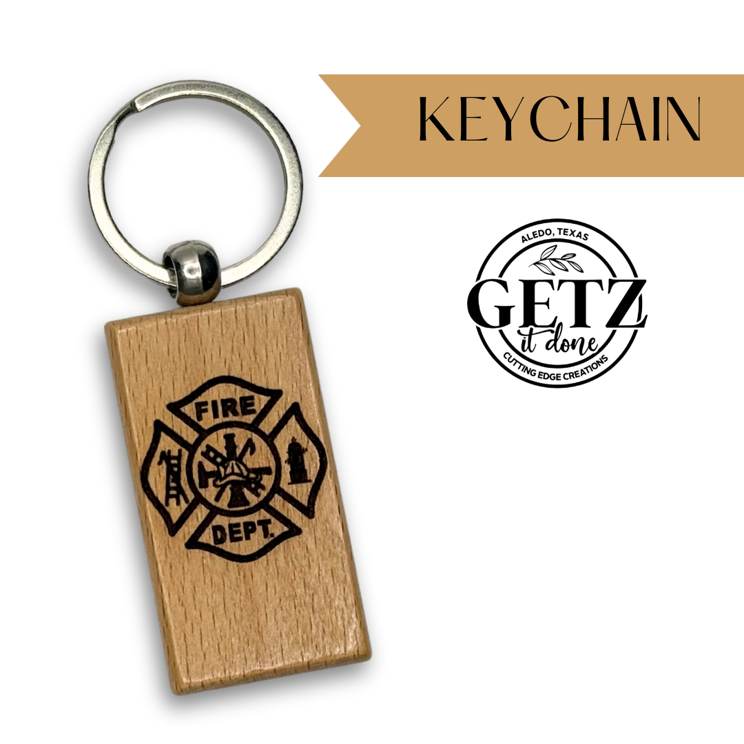 A rectangular wooden keychain displays a FIRE DEPT. emblem with a fireman’s helmet, ladder, and hydrant. To the right, KEYCHAIN is written on a tan banner. Below, the GETZ it done logo with Aledo, Texas and Cutting Edge Creations encircle the text.