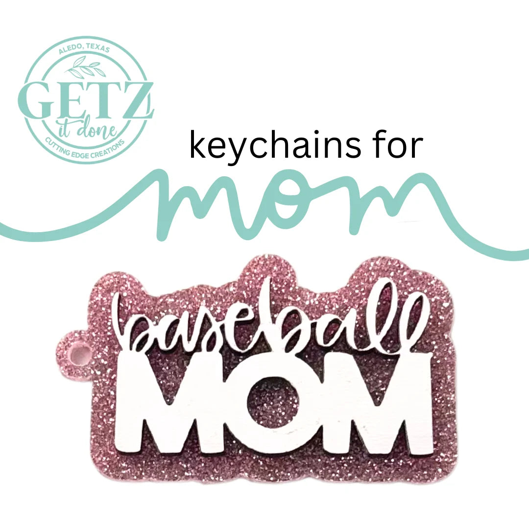 A glittery pink keychain in the shape of a home plate features the words baseball MOM in white. Above, the text keychains for mom is styled with mom in cursive writing. The background shows the logo of GETZ it done in green, with Aledo, Texas and Cutting Edge Creations around it.
