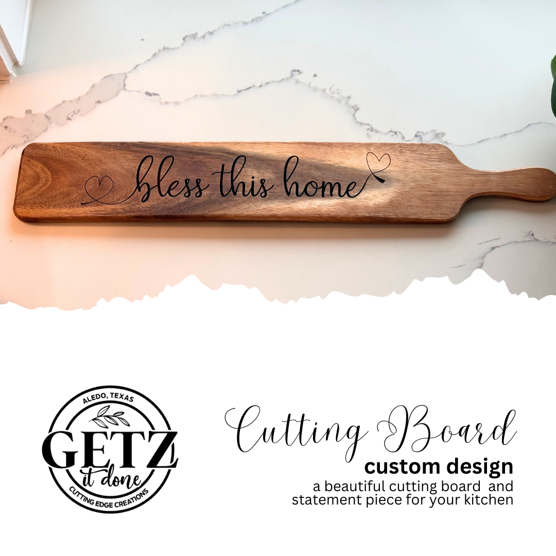 Wooden cutting board with a handle, engraved with bless this home and small heart designs. The background features a marble countertop. Below the board is a logo that reads GETZ it done and the text Cutting Board custom design—a beautiful cutting board and statement piece for your kitchen.