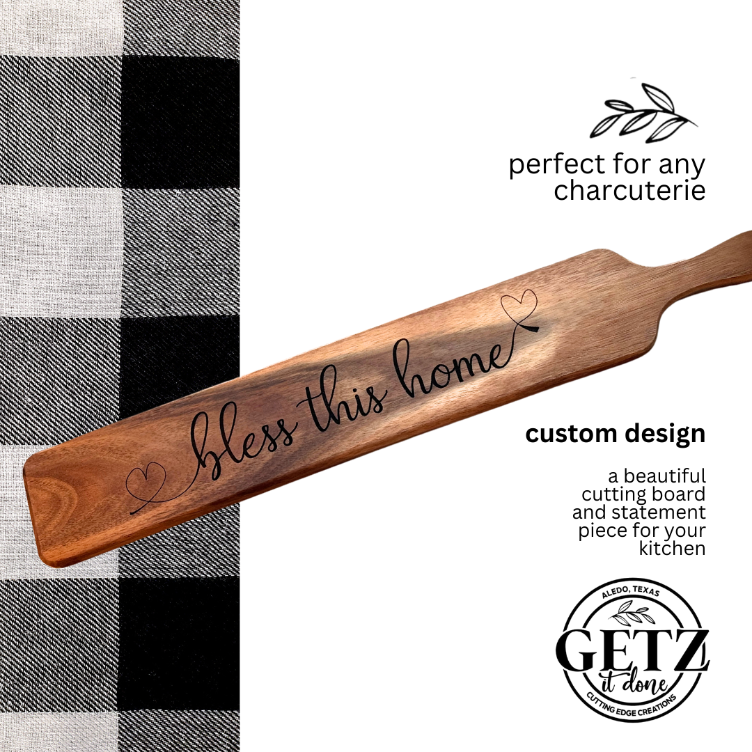 A wooden charcuterie board with bless this home written in cursive, featuring small heart motifs. Its positioned on a black and white checkered fabric. Text reads, perfect for any charcuterie, custom design, with GETZ done logo at the bottom.