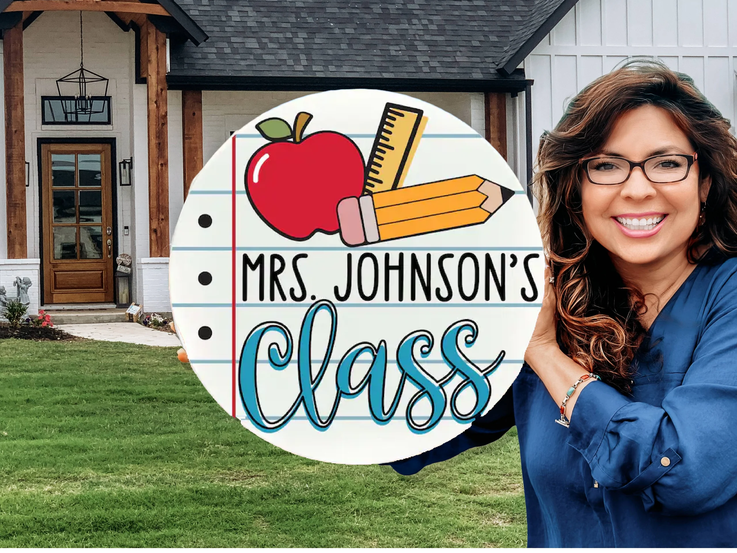 A smiling woman with long brown hair and glasses stands outside a house, holding a round sign with an apple, pencils, and ruler that reads Mrs. Johnsons Class.