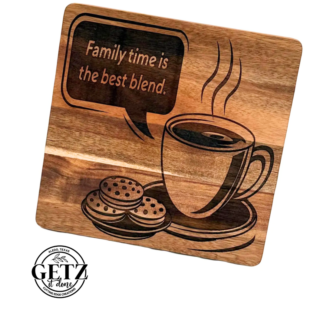 A wooden cutting board features an engraved design of a steaming coffee cup and a plate with cookies. Above, a speech bubble reads, Family time is the best blend. A logo in the bottom left corner states Getz It Done with Waco, Texas, adorned with two branches.