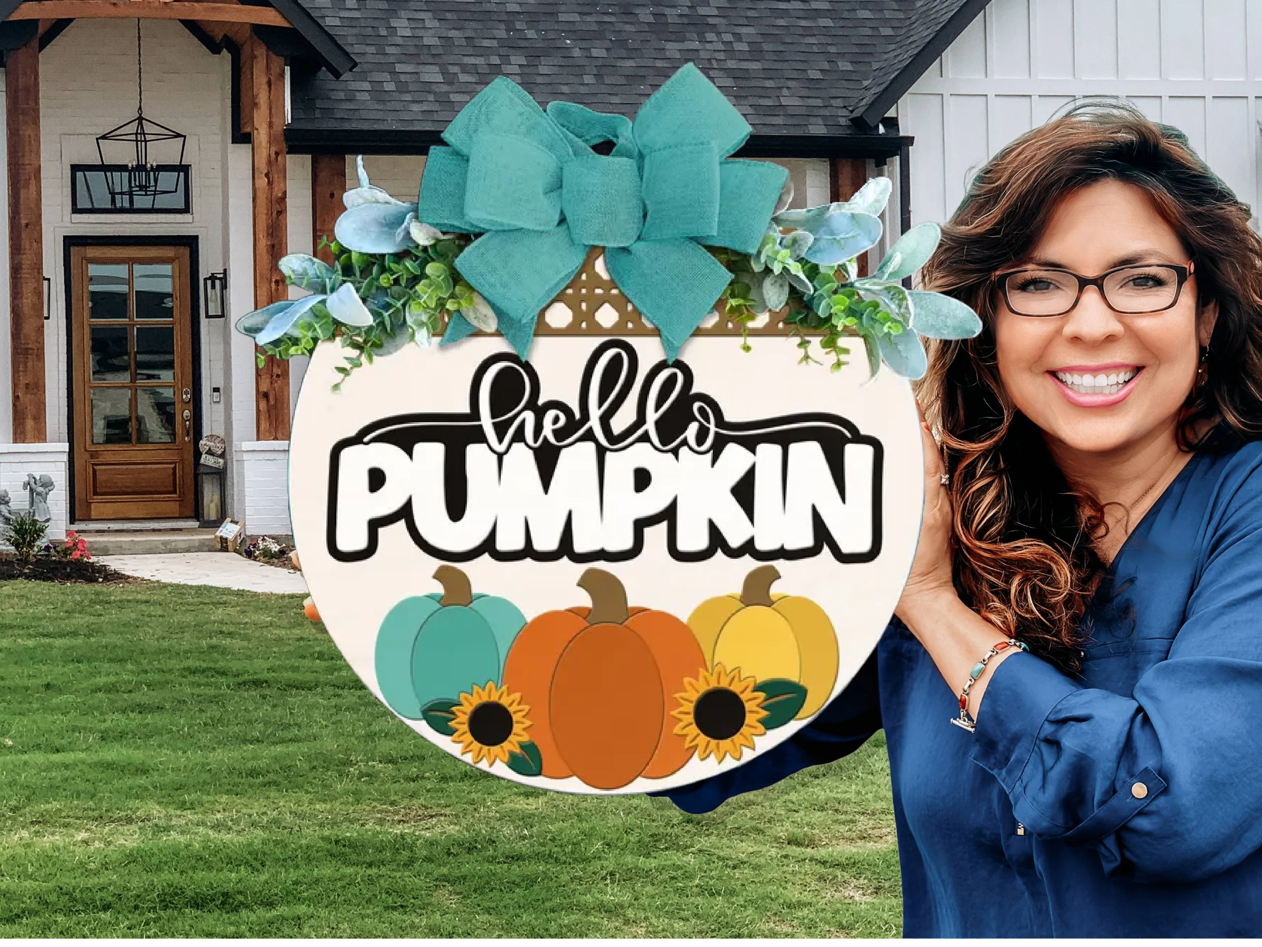 A smiling woman with glasses holds a round sign decorated with pumpkins, sunflowers, greenery, and a teal bow. The sign says Hello Pumpkin. She stands in front of a modern house with a lawn.