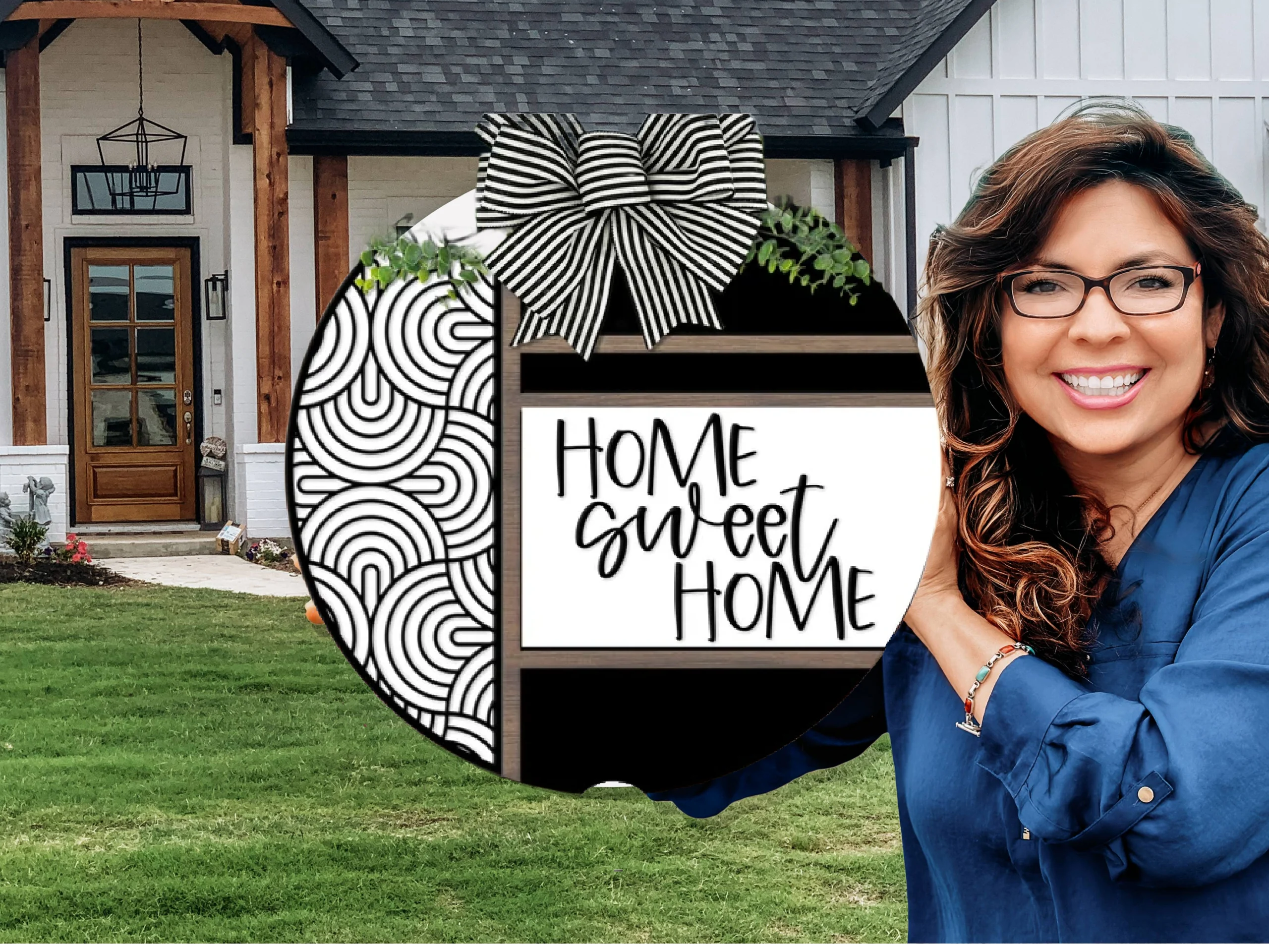 A smiling woman with wavy hair and glasses holds a round sign that reads Home Sweet Home in front of a modern house with white walls, wood accents, and a green lawn.