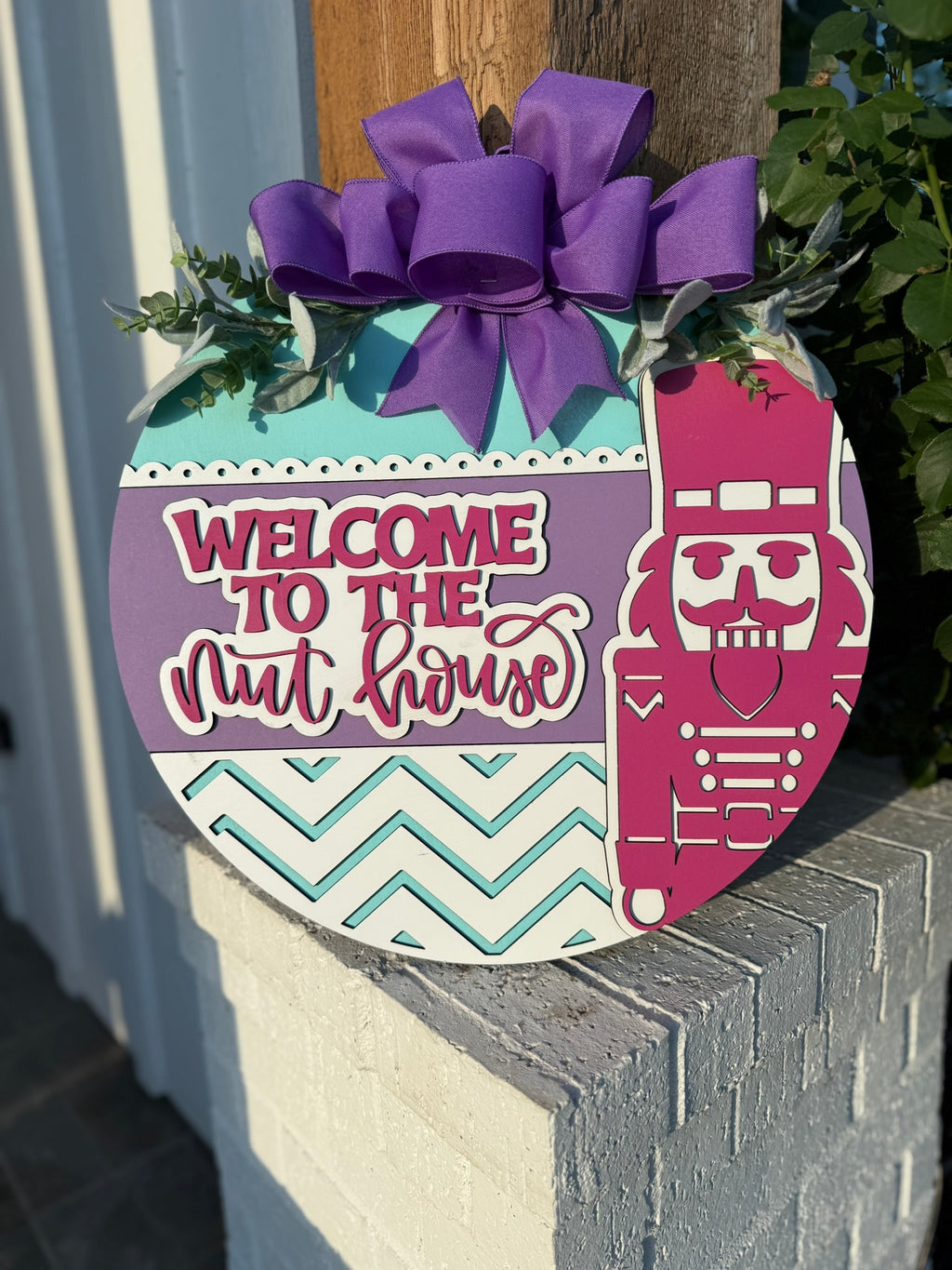 Welcome to the Nut House Door Sign – Nutcracker Christmas Wreath, 3D Layered Wooden Holiday Door Hanger with Purple Bow (16–20”)