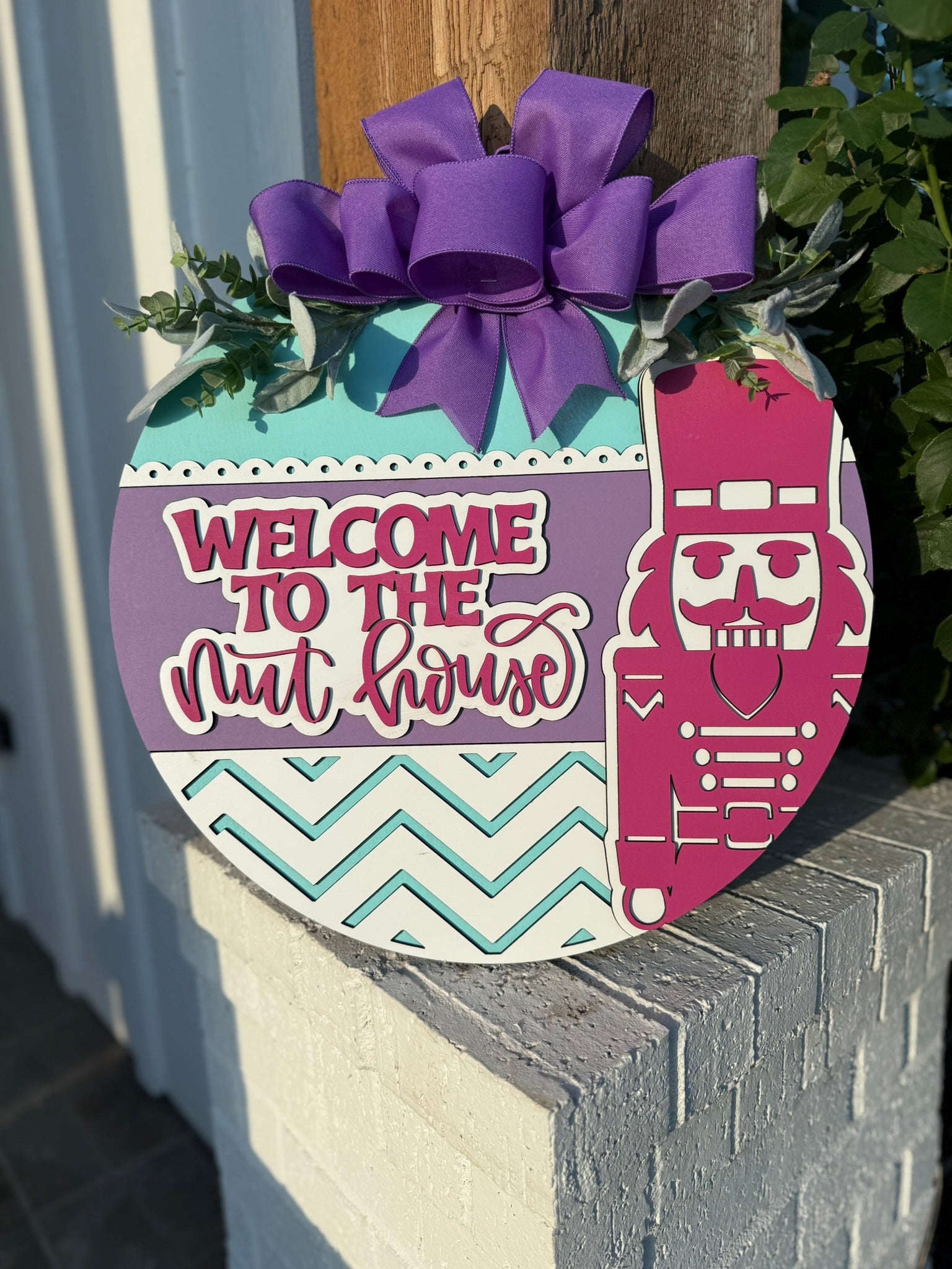 Welcome to the Nut House Door Sign – Nutcracker Christmas Wreath, 3D Layered Wooden Holiday Door Hanger with Purple Bow (16–20”)