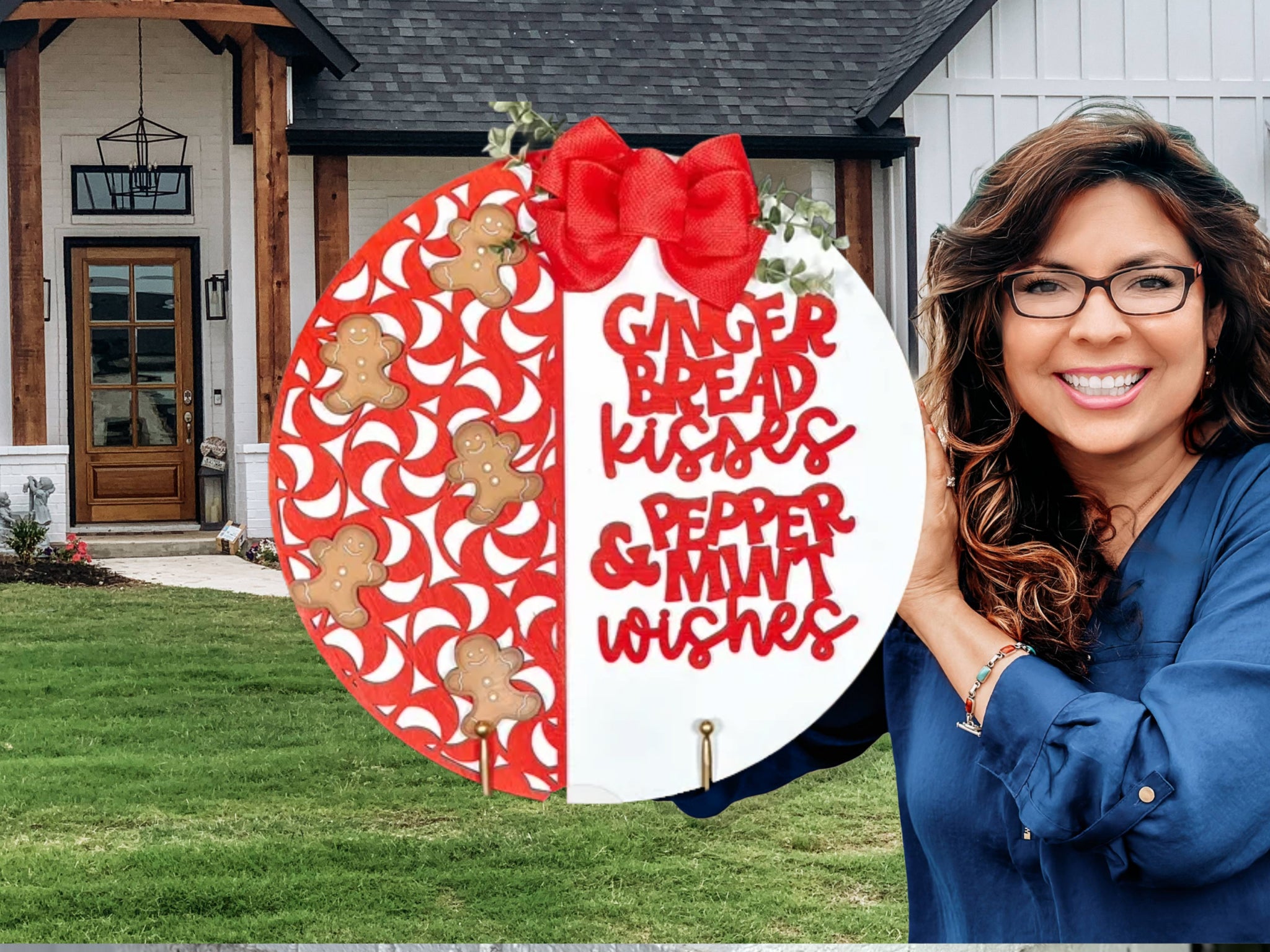 A smiling woman with wavy brown hair and glasses holds a round holiday sign decorated with gingerbread men, red peppermints, and a red bow. The sign reads, Gingerbread kisses & peppermint wishes. A house is in the background.