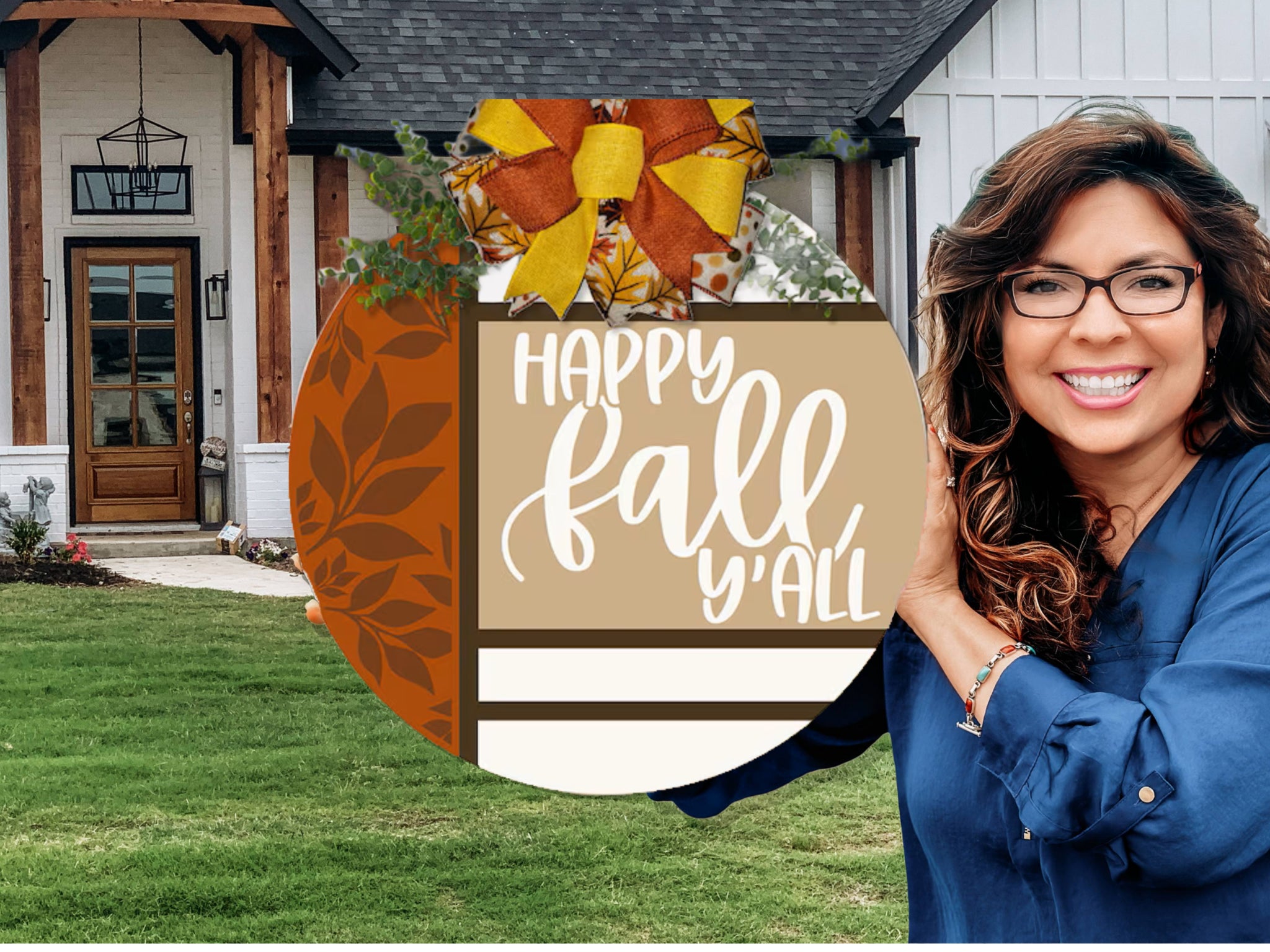A smiling woman wearing glasses holds a round sign that says Happy Fall Yall in front of a modern house with a wooden front porch and a green lawn.