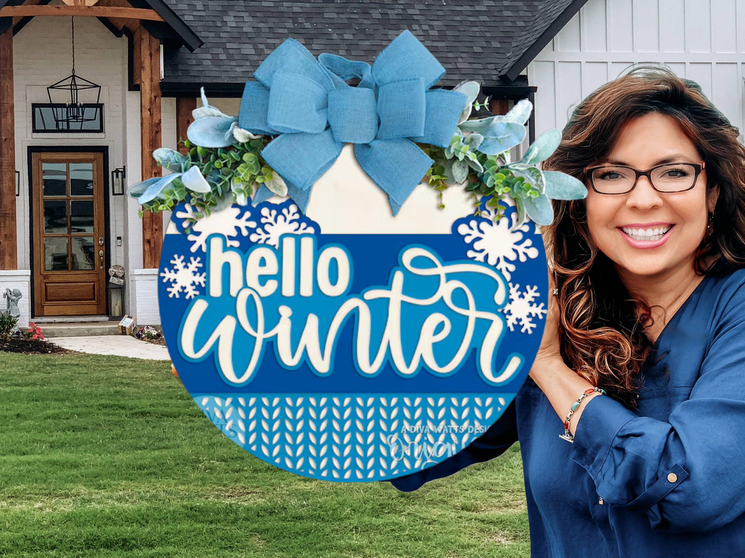 A smiling woman wearing glasses holds a blue and white circular sign decorated with leaves, a bow, and snowflakes. The sign reads hello winter. She stands outside a house with a lawn and modern wooden door.