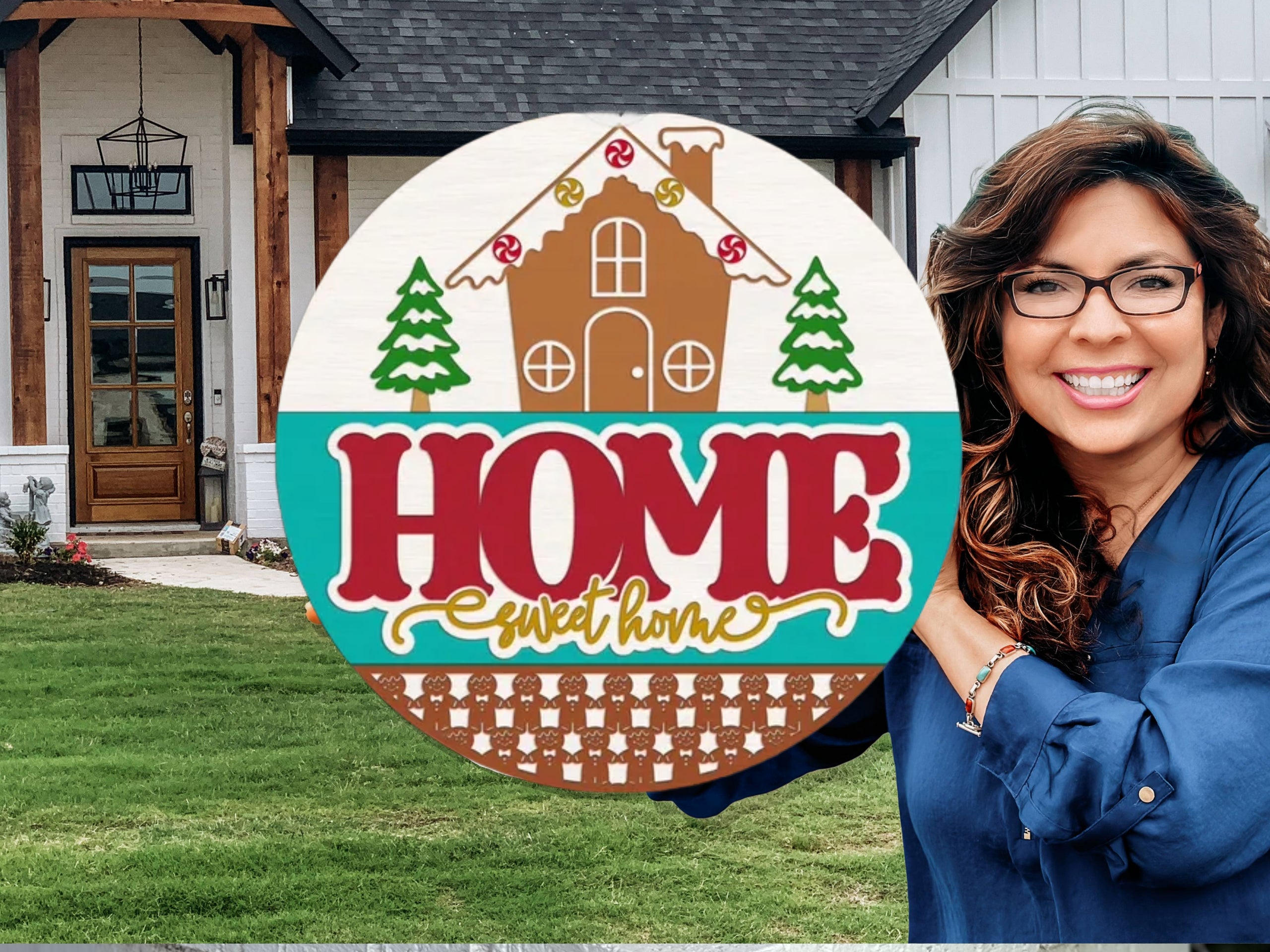 A decorative round sign with a gingerbread house, candy decorations, pine trees, and the words “HOME sweet home” in bold red and yellow letters, displayed on a white brick ledge with greenery nearby.
