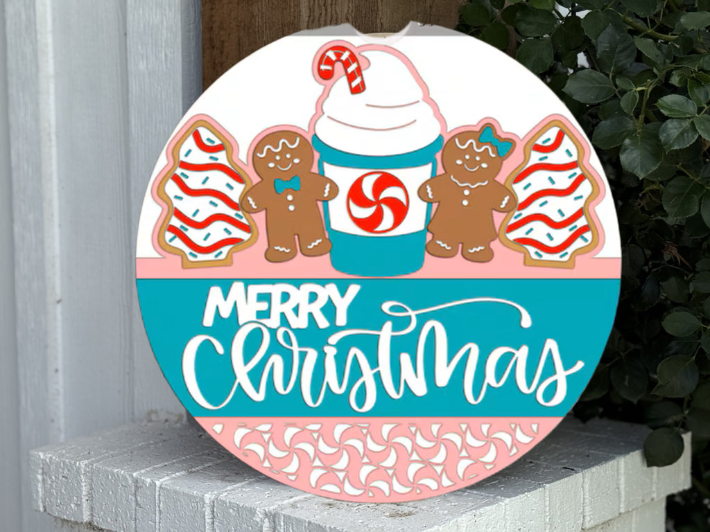 Round Christmas sign featuring two decorated gingerbread cookies, two frosted tree cookies, and a festive drink with a peppermint swirl and candy cane. The words Merry Christmas are written in white script.