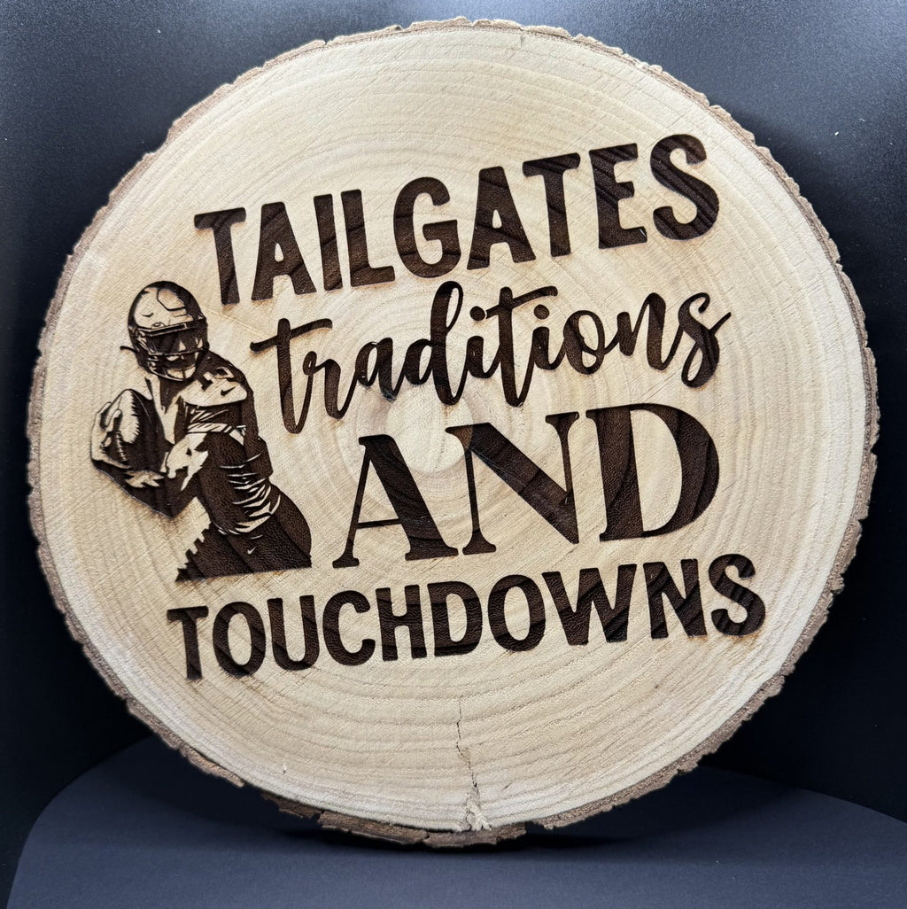 The Football - Wood slice wall decoration features engraved words TAILGATES, TRADITIONS, AND TOUCHDOWNS alongside a football player in gear. Its natural texture and circular shape make for the perfect decorative piece against a dark backdrop.