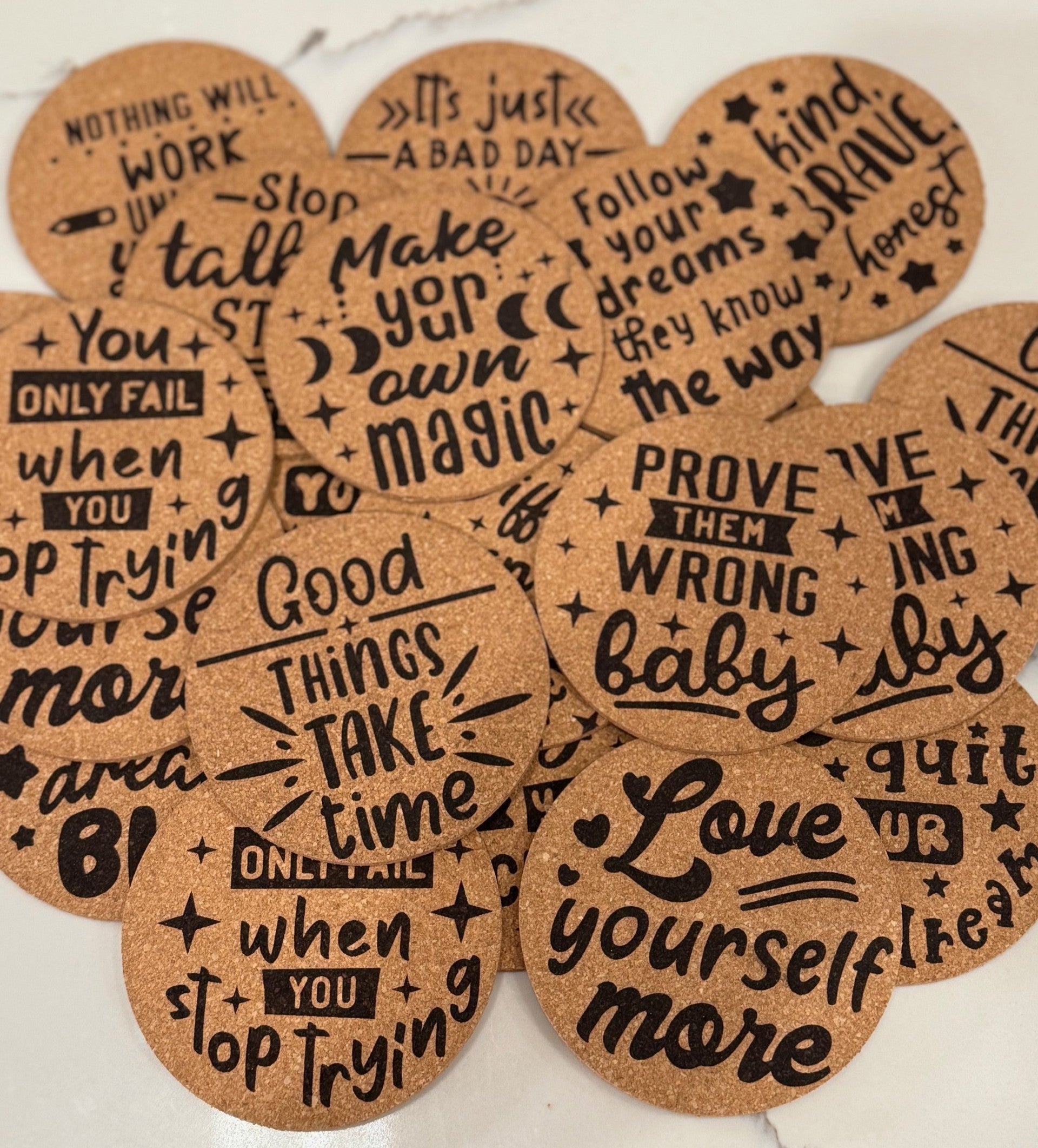 The Motivational Cork Coasters - Set of 4 feature inspiring quotes like Good things take time, Love yourself more, Prove them wrong baby, and Only fail when you stop trying in bold black text. Protect your surfaces while staying motivated with these stylish coasters.