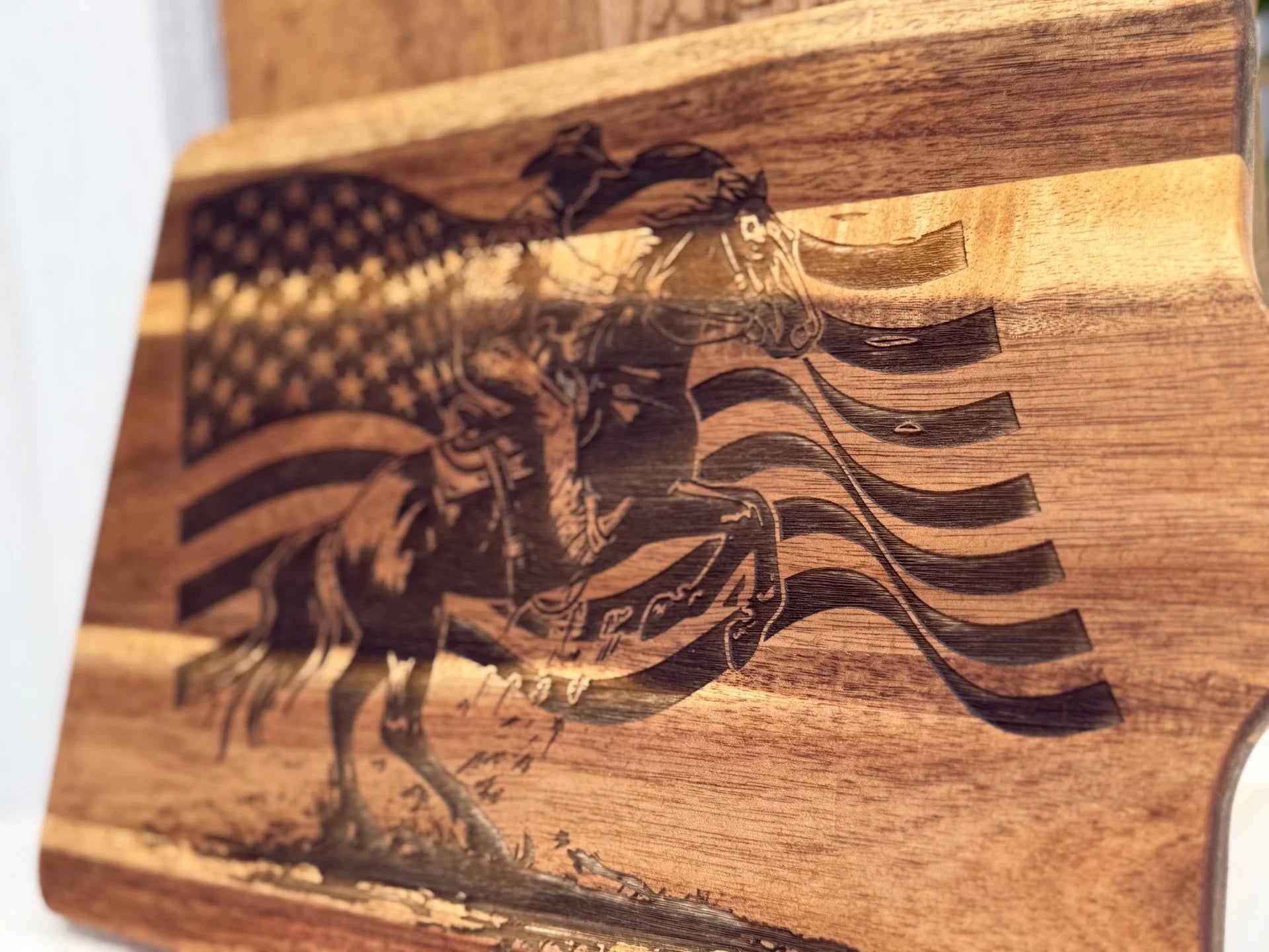 A wooden board features an engraved image of a cowboy riding a bucking horse with a waving American flag in the background.