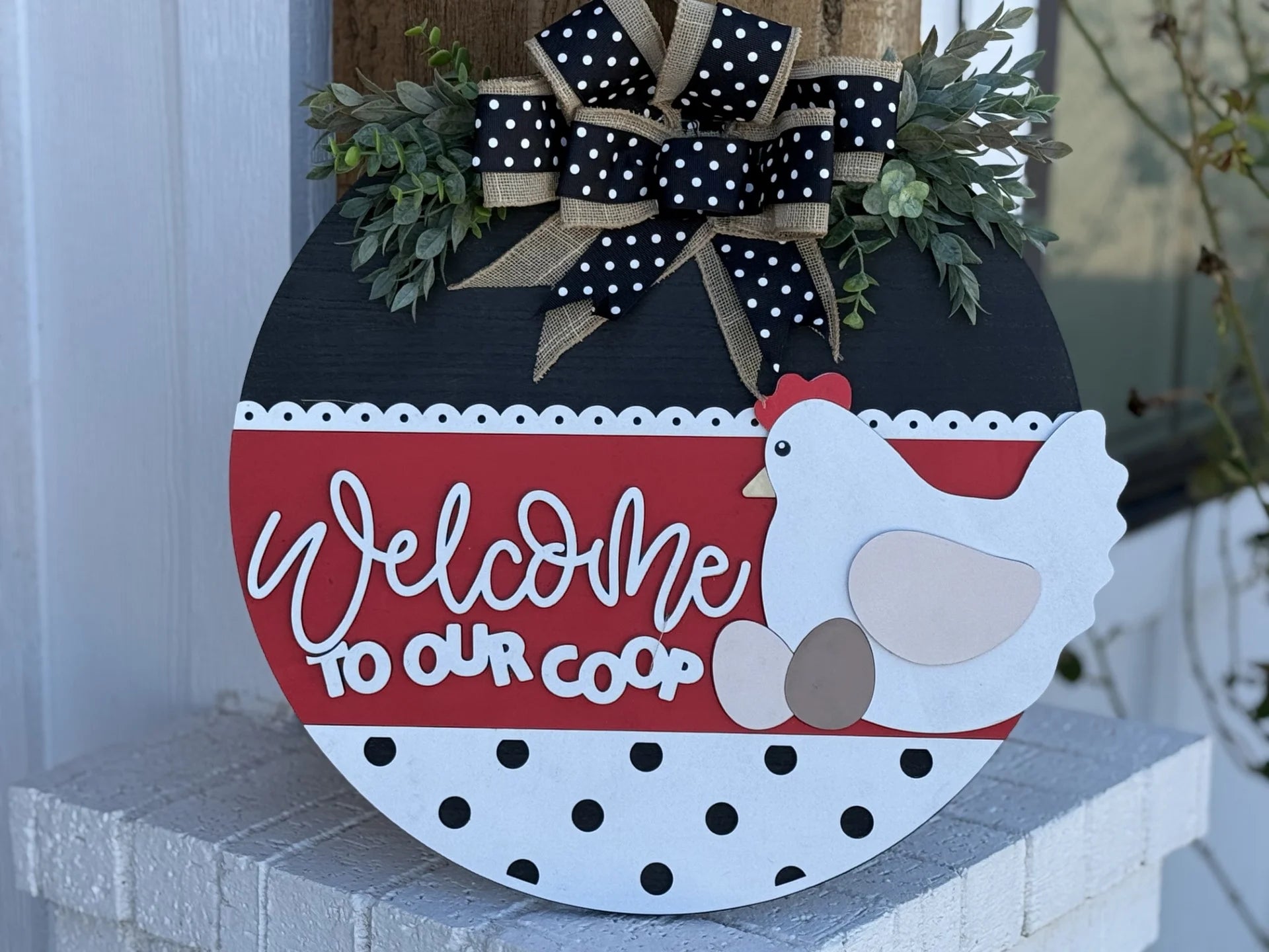 Greet guests with the If Were Not Home Check the Rink door wreath. Featuring a round design with a black top, red middle, white polka-dotted bottom, and adorned by a black-and-white bow, it showcases a stylish chicken and eggs motif—a charming addition to your homes entrance.