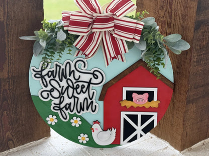 Round wooden sign with Farm Sweet Farm in cursive black letters. It features a red barn with a pig, a chicken, and daisies. Eucalyptus leaves and a large red and white striped bow adorn the top. The background includes blue sky and green grass.