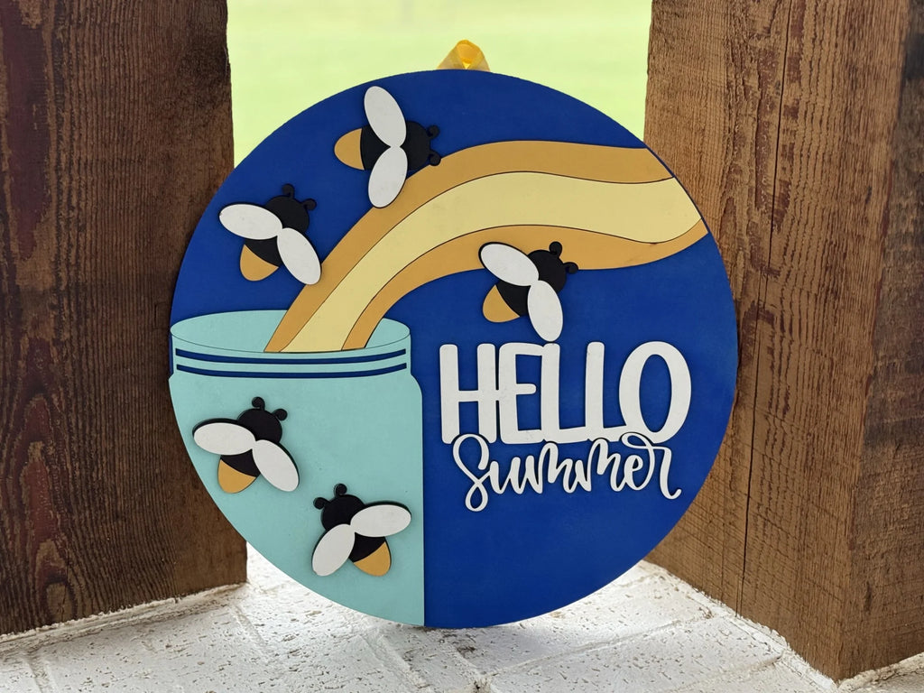 A round sign with a blue background shows lemonade being poured into a glass, surrounded by cartoon bees. The words HELLO summer are written in white cursive and block letters at the bottom right.