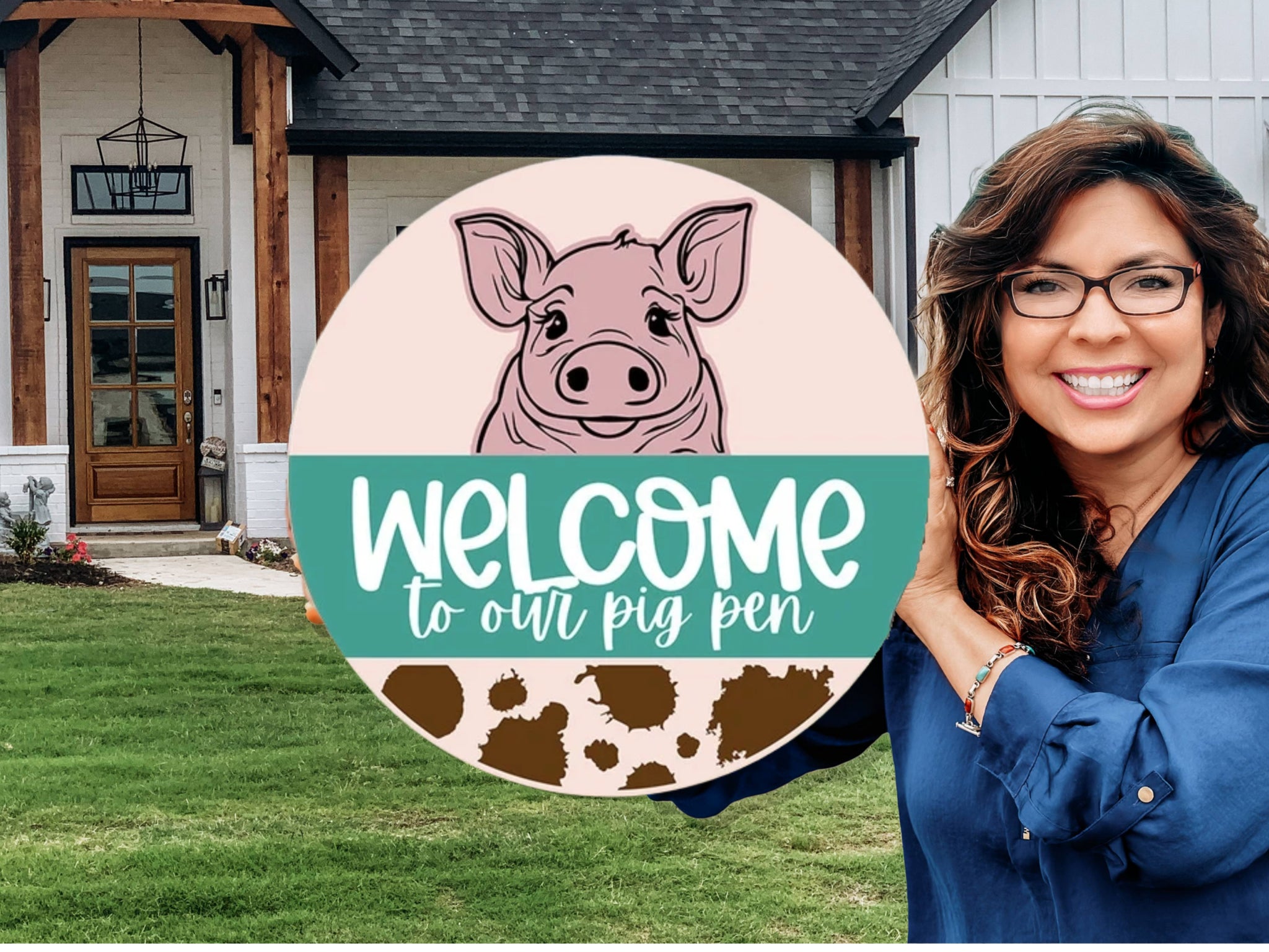 A smiling woman stands in front of a modern house, holding a circular sign that reads “Welcome to our pig pen” with a drawing of a pig and brown spots.