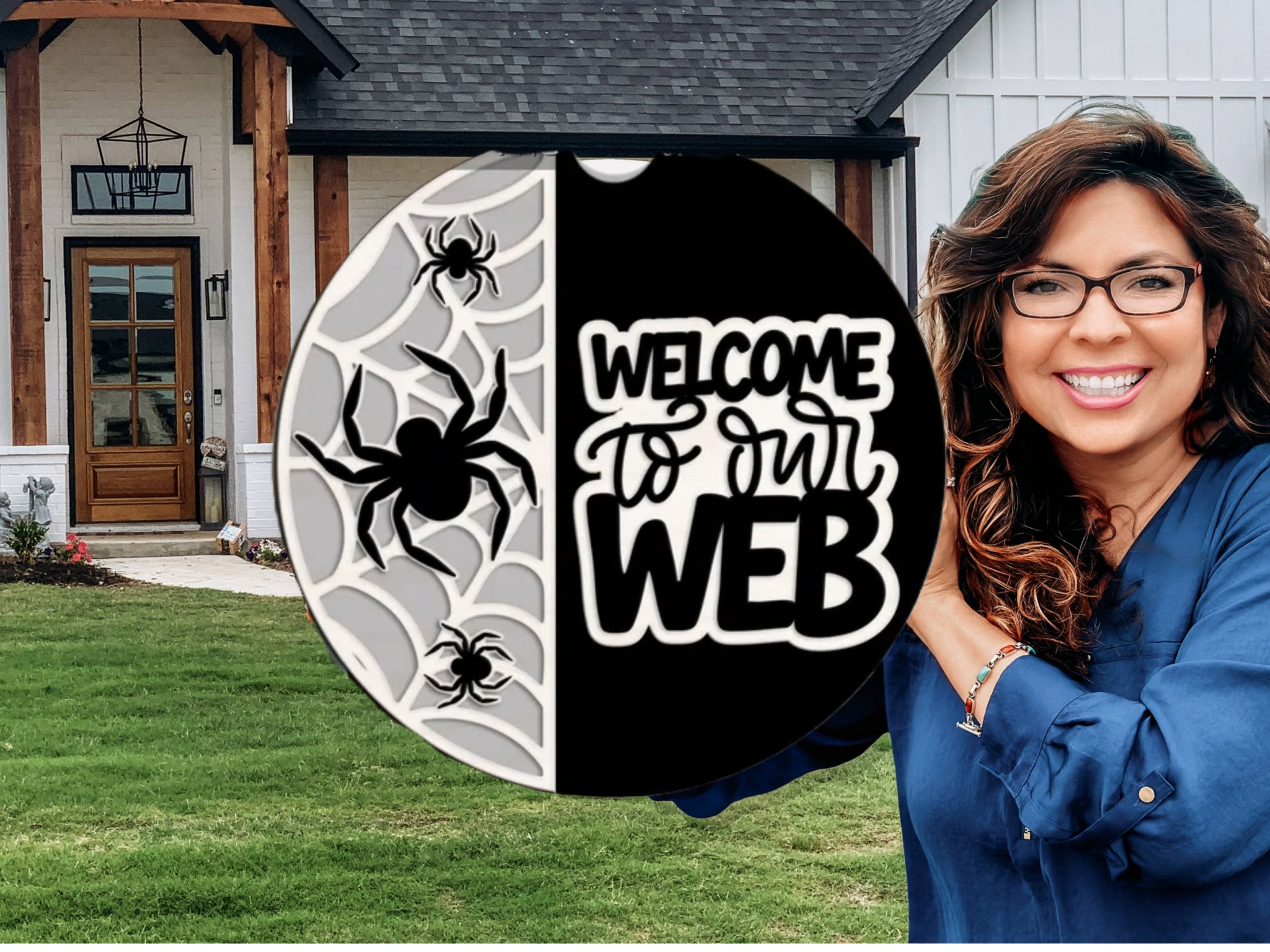 A smiling woman holding a round sign with spiderwebs, spiders, and the text Welcome to our WEB stands in front of a modern house with a green lawn.